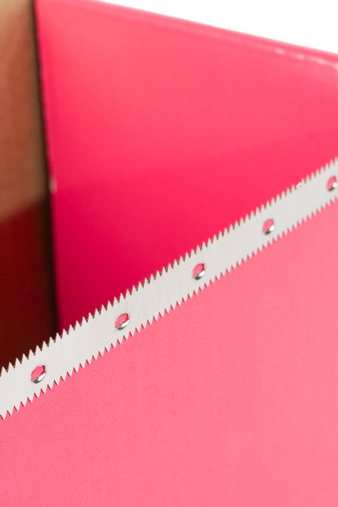 Inside edge of the pink dispenser box showing the serrated cutting strip for tearing off foil