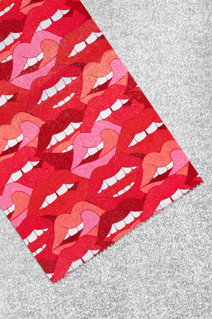 Foil sheet folded back to show the print up close: overlapping red, pink and coral lips with white teeth. Plain silver on the reverse side.