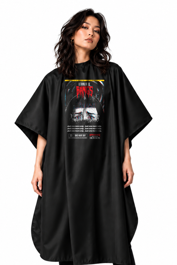 A model wearing a black salon cape with a large graphic print on the front featuring the Bangs Hair Raiser Print
